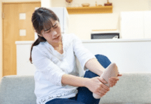 femme assise massant sa jambe avec un stimulateur circulatoire pour prévenir les varices