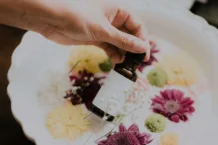 main appliquant une huile essentielle sur des fleurs séchées colorées