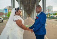 Robe petite taille pour mariage invitée : les coupes qui allongent A joyful couple holding hands during their wedding in Paris, captured under an iconic bridge.