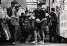 Porter un foulard en soie : 15 façons stylées en 2026 Porters working in a busy market, captured in black and white for a classic look.