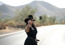 A woman in short shorts and a hat on the side of the road